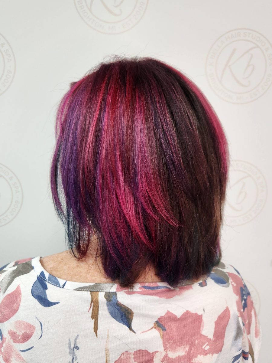 Side view of finished bob-length haircut with burgundy and magenta vivid color by Siobhan Rozinski at K Bella Hair Studio & Spa in Brighton, MI
