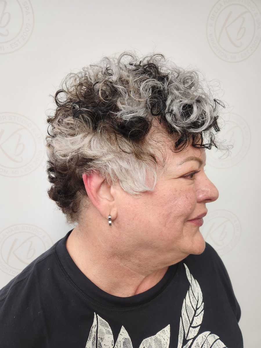 Side profile of curly cropped hair showing cut definition and warm-to-cool color blocking by Siobhan Rozinski at K Bella Hair Studio & Spa in Brighton, MI