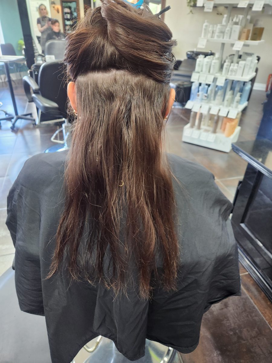 Back view of long brunette hair sectioned and clipped on top, with lighter-toned balayage placement visible on lower sections, by Siobhan Rozinski at K Bella Hair Studio & Spa in Brighton, MI