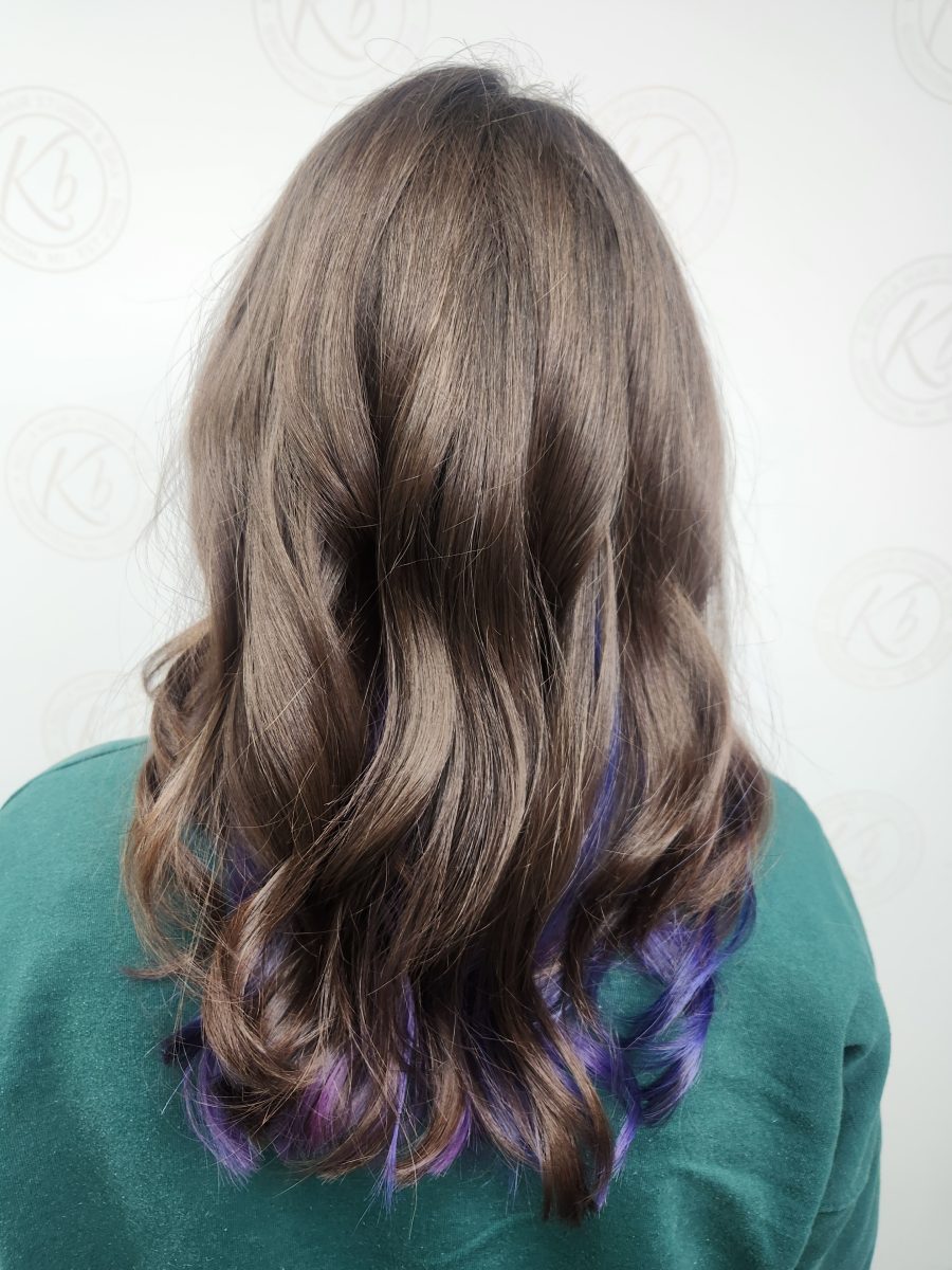 Back view of long brunette hair with vivid purple peekaboo highlights and layers, styled with waves, by Siobhan Rozinski at K Bella Hair Studio & Spa in Brighton, MI