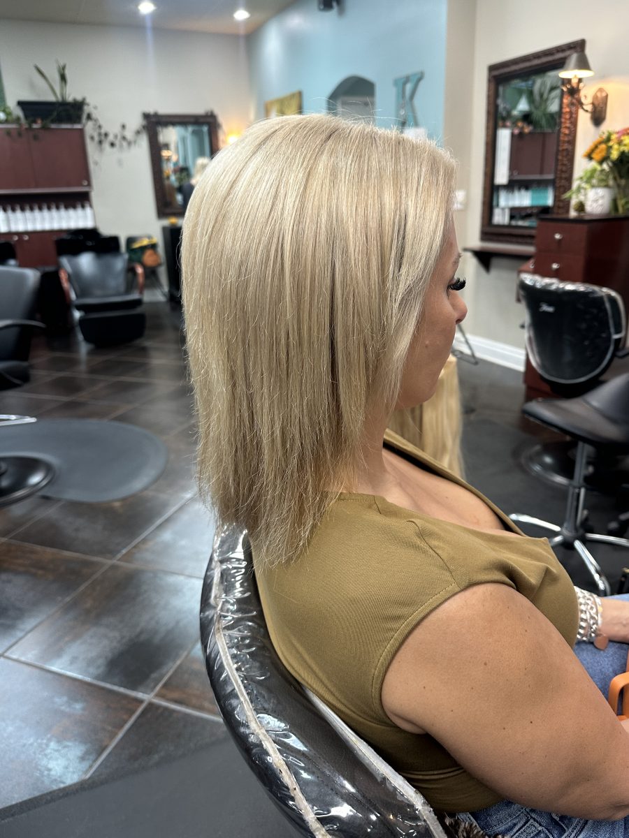 Before: Back view of long blonde hair with soft waves, showing volume weft extensions by Kameryn Bell at K Bella Hair Studio & Spa in Brighton, MI