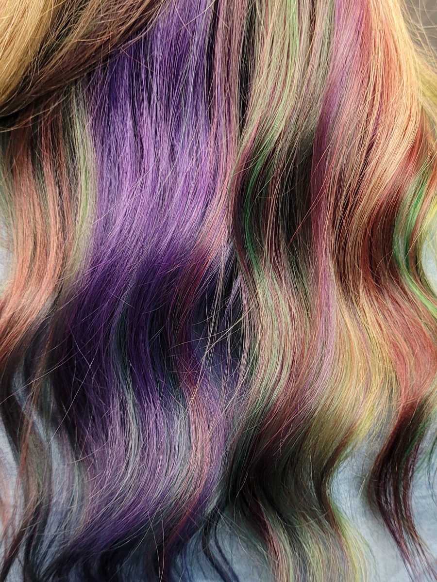 Close-up texture of multi-colored hair strands showing purple, pink, yellow, and green tones by Kristan Sayers at K Bella Hair Studio & Spa in Brighton, MI