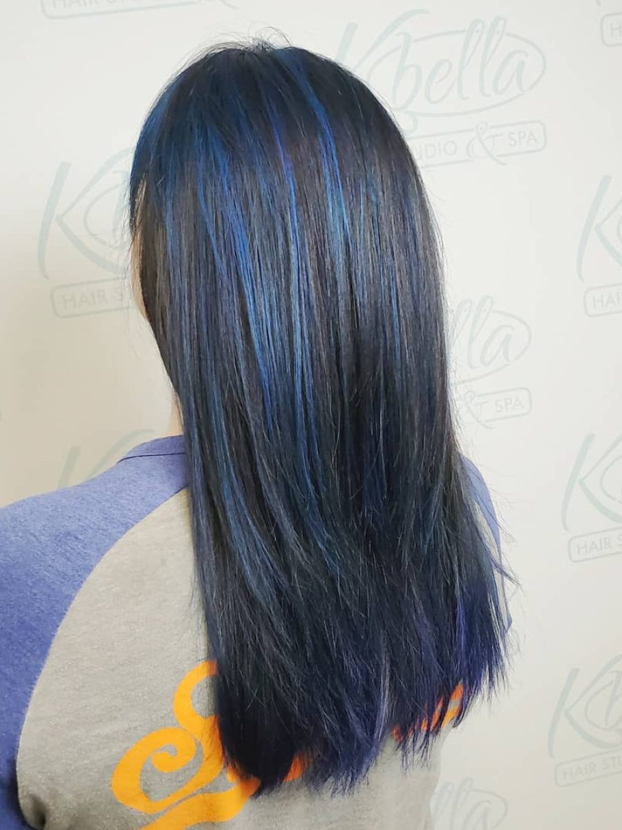Back view of shoulder-length hair with layered texture and vibrant blue streaks against a blue-black base by Kristan Sayers at K Bella Hair Studio & Spa in Brighton, MI