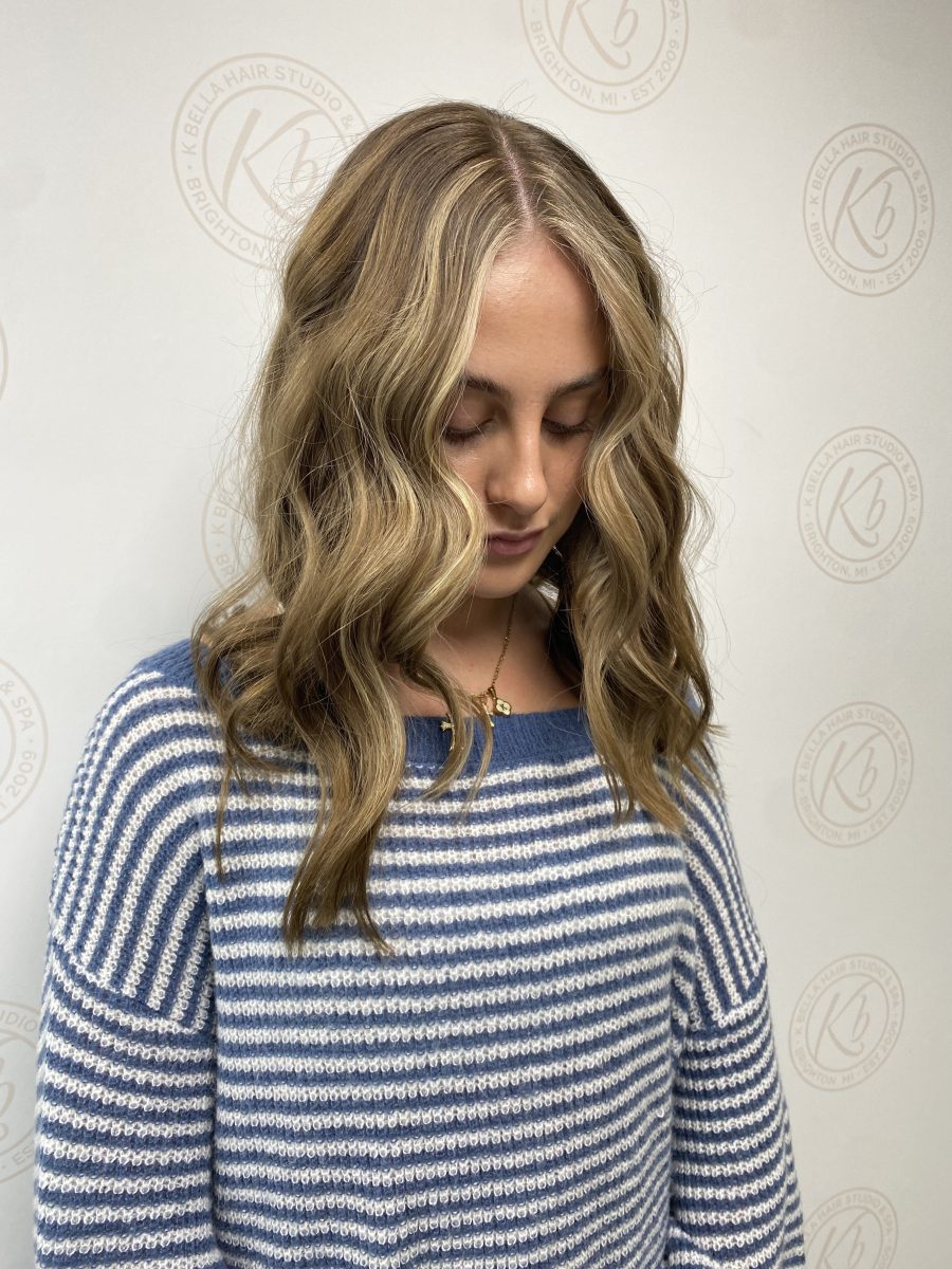 Front-facing view of long wavy hair with blonde money pieces framing the face by Abbey French at K Bella Hair Studio & Spa in Brighton, MI