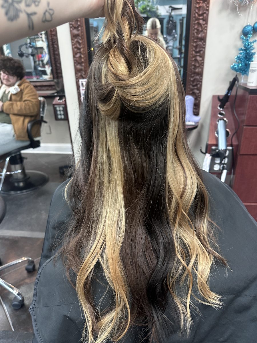 Back view of long wavy hair styled in calico color, showing dimensional blonde and dark tones by Kameryn Bell at K Bella Hair Studio & Spa in Brighton, MI