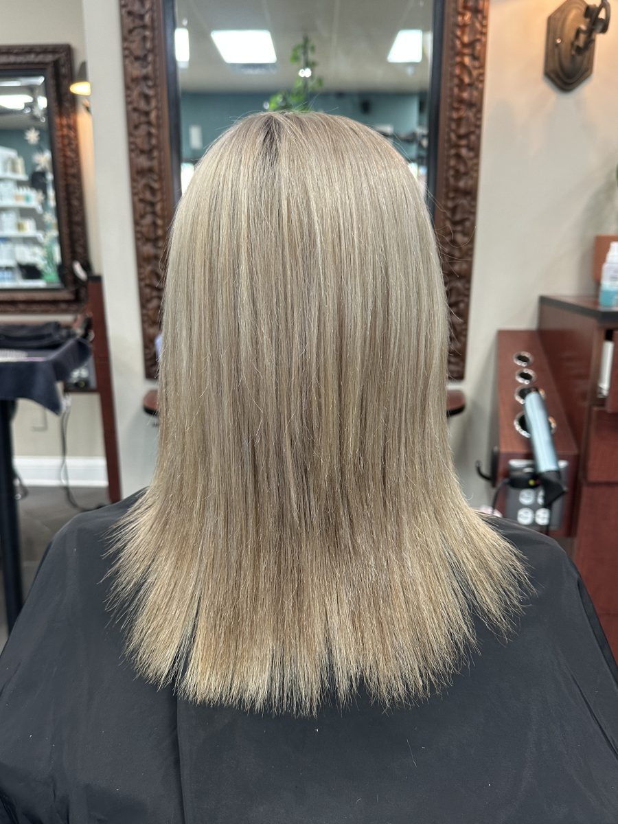 Rear view of medium-length blonde hair before the cut, with longer, heavier ends, by Kameryn Bell at K Bella Hair Studio & Spa in Brighton, MI