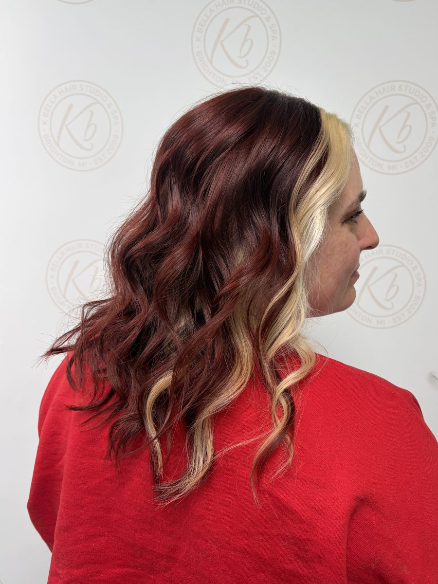 Side profile of wavy hair showing blonde-to-burgundy color blend and wave texture by Abbey French at K Bella Hair Studio & Spa in Brighton, MI