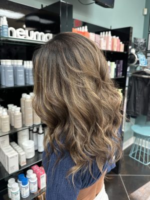 Side profile view of long wavy hair with deepened roots and golden blonde highlights by Liberty Greenwood at K Bella Hair Studio & Spa in Brighton, MI