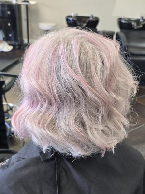 Back view of a short layered bob with pink and blonde balayage, styled with soft waves by Kristan Sayers at K Bella Hair Studio & Spa in Brighton, MI