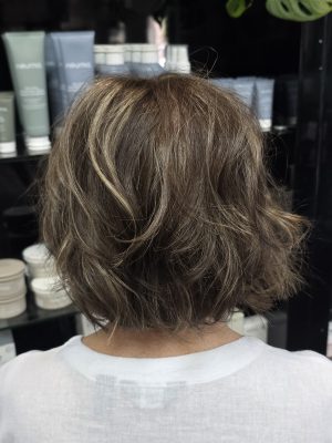 Back view of a short graduated bob with chunky highlights in vanilla blonde and dark golden brown by Kristan Sayers at K Bella Hair Studio & Spa in Brighton, MI