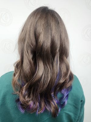 Back view of long brunette hair with vivid purple peekaboo highlights and layers, styled with waves, by Siobhan Rozinski at K Bella Hair Studio & Spa in Brighton, MI